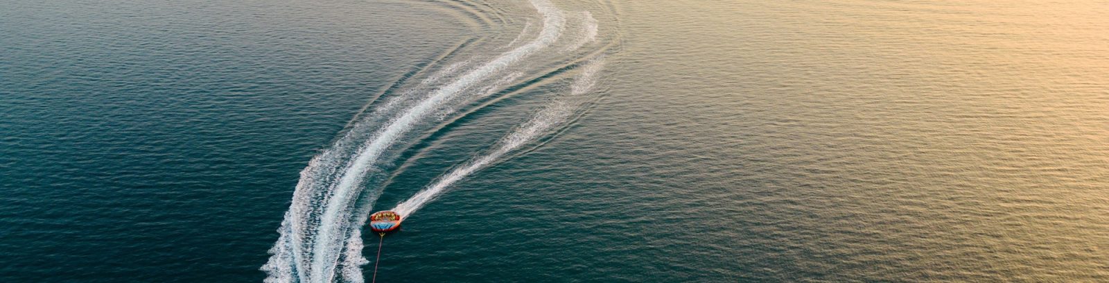 Drone view of people having fun on jet ski tubes in the middle of the sea